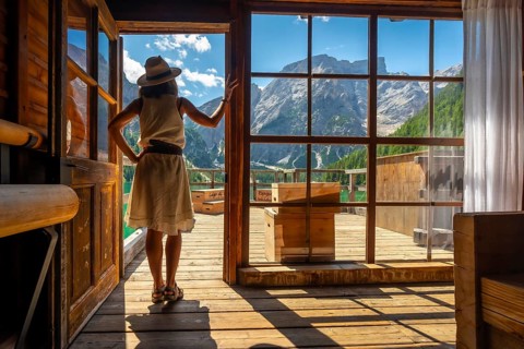 Woman enjoying breathtaking views of lake braies and surrounding mountains from a traditional