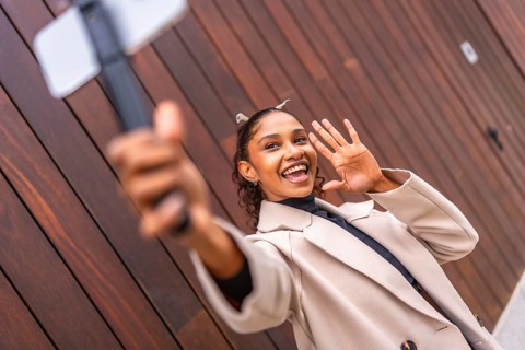 African american young female Content creator recording a new vlog using phone in the city