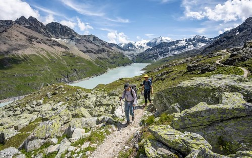 Two mountaineers on a hiking trail, view of a blue mountain lake, Lac des Dix reservoir, mountain