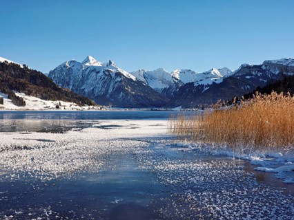 Frozen Sihlsee, reservoir, behind the snow-covered mountains Flübrig and Druesberg, Euthal, Canton