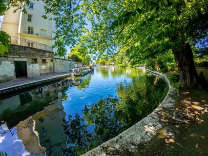 Calm waters reflecting buildings and lush trees along little venice canal in london, offering a
