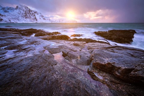Beach of Norwegian sea on rocky coast in fjord on sunset in winter. Vareid beach, Lofoten islands,
