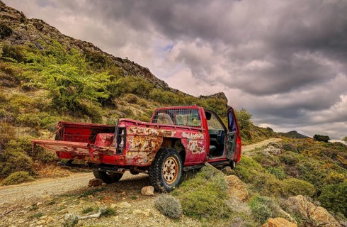 An old, rusty pickup truck in mountainous nature under a cloudy sky, wrecked vehicle, Crete, Greek