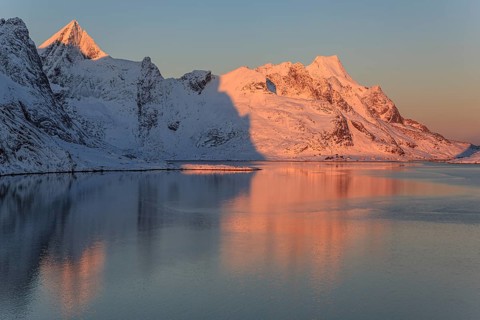 Snow-covered mountains reflected in the fjord at sunrise, winter, Reine, Moskenesoya, Lofoten,