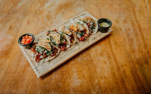 Traditional tacos al pastor with sauces served on a wooden board. Delicious Mexican chicken tacos