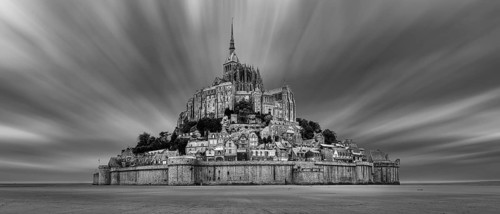 Impressive view of Mont Saint-Michel in black and white, surrounded by dramatic clouds, Le