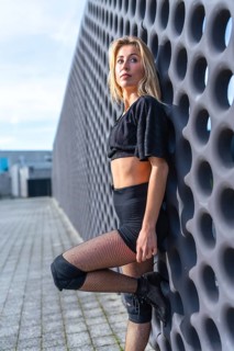 Young urban dancer striking a pose in high heels, knee pads, and fishnet stockings, exuding