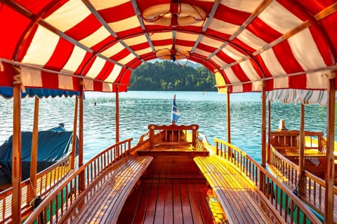 Wooden tourist boat with red and white canopy sailing on lake bled in slovenia, offering scenic