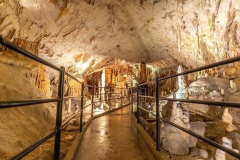 Tourists are enjoying a visit inside postojna cave in slovenia, walking on illuminated footpath