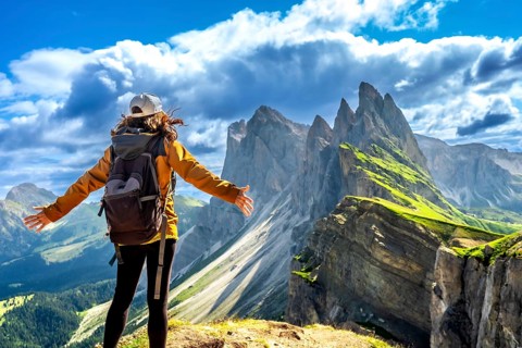 Backpacker enjoying breathtaking panorama of the odle mountain range during summer adventures in