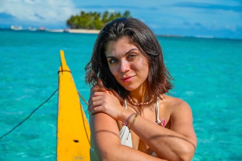 Young woman relaxing on traditional outrigger boat, enjoying the turquoise waters of daku island in