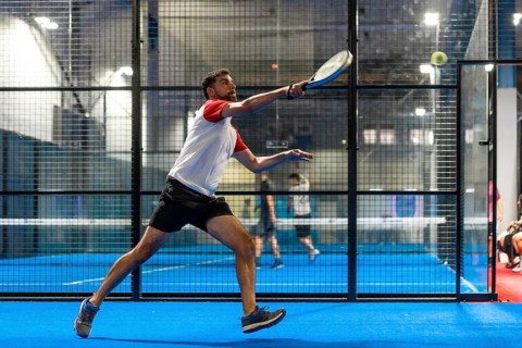 Full length photo of a mature sportive man trying to reach the ball while playing paddle tennis in
