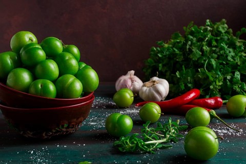 Tkemali, green cherry plum, with ingredients for sauce, cilantro, mint, hot pepper, garlic, on a