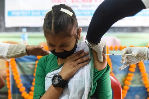 A health worker inoculates a student with a dose of a Covid-19 coronavirus vaccine during a