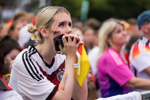 A woman watches the football match in the fan zone at the Brandenburg Tor during the quarter-final