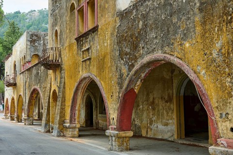 Street with dilapidated yellow historic-style buildings characterised by arches, balconies and