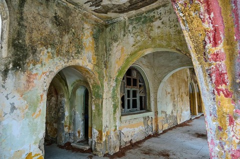 Abandoned rooms with dilapidated walls and arches, overgrown and in a state of decay, Italian