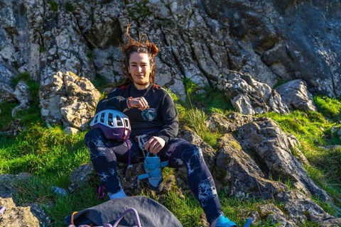 Young climber woman resting on a mountain after her climbing activity, checking her smartwatch