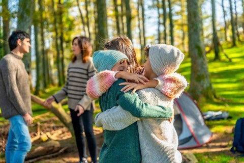 Three young caucasian children embracing enjoying camping day in the forest with family