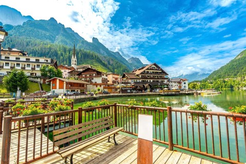 Tourists strolling along the picturesque shores of alleghe lake in the stunning dolomites on a