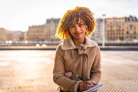 Beauty latin woman sketching on notebook sitting in the city