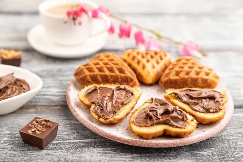 Homemade waffle with chocolate butter and cup of coffee on a gray wooden background. side view,