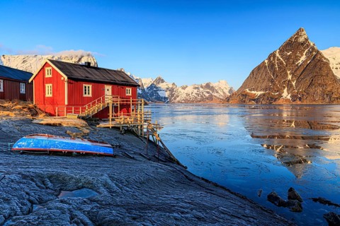 Red wooden house at fjord in front of Bergen, morning light, reflection, winter, Reine,