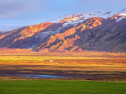 View over meadows to glacier Eyjafjallajökull, Fljotsdalur valley, warm light at sunset, Iceland,
