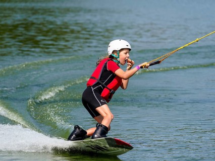 Boy or girl with wakeboard in lake, eating bread, water sports, water skiing in wakepark