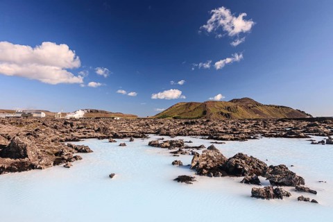 Outdoor thermal pool and geothermal power plant in front of volcanic mountains, Blue Lagoon,