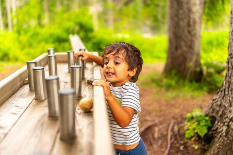 Young child exploring and interacting with a sensory play station in a natural park setting,