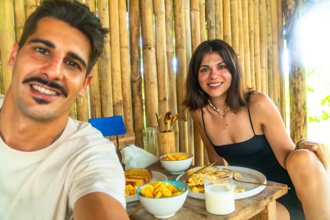 Tourists having breakfast with mango and scrambled eggs in a bamboo hut during their holidays in