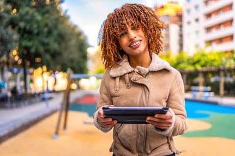 Frontal portrait of a beauty and happy latin woman holding digital tablet working outdoors