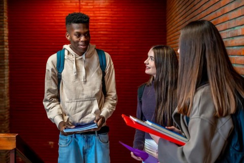 Group of cheerful multi ethnic students talking and smiling together on school hallway during break