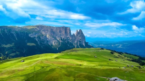 Breathtaking summer landscape featuring lush green meadows, rolling hills, and the majestic peaks