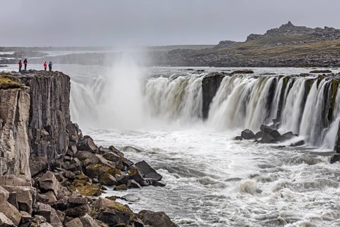 People standing in front of a waterfall at a river, cascades, spray, rapids, summer, foggy,