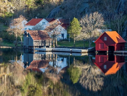 Fjord near Ana Sira at the norwegian southern coast, lonely houses at the foot of a rock formation,