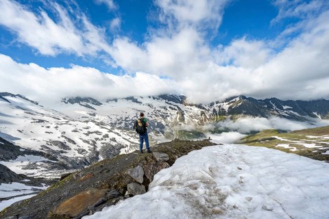 Mountaineer on hiking trail between snowfields, mountain landscape with summit Hoher Weißzint and