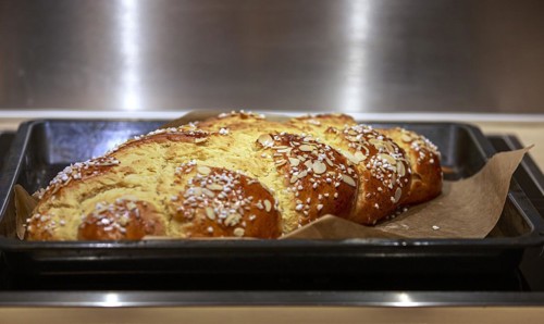 Golden-brown, crispy yeast plait with sugar and almond slivers on a baking tray