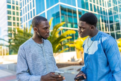 Two senegalese businessmen wearing traditional dashiki attire are discussing business while holding