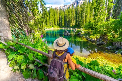 Mother and child enjoying breathtaking view of lake carezza's turquoise waters, surrounded by lush