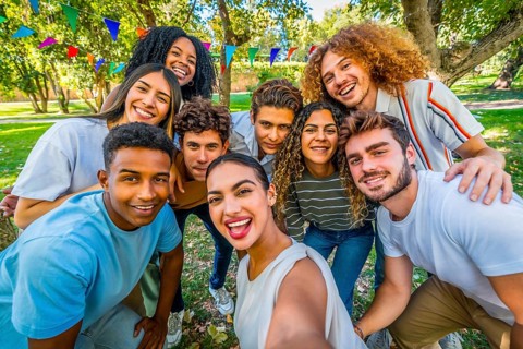 Frontal personal perspective view of a caucasian young woman taking selfie during party in a park
