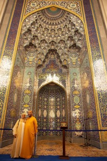 Omani couple in traditional dress in front of the golden prayer niche in the Sultan Qabus Grand