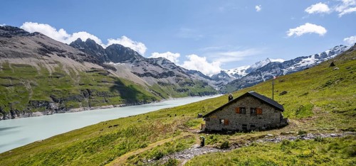 Alpine hut on a blue mountain lake, Lac des Dix reservoir, behind mountain peak Mont Blanc de