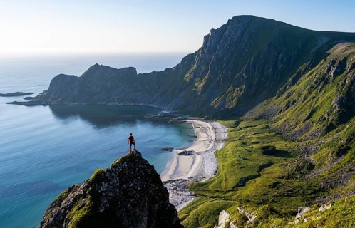 Climber on a rock, view of picturesque coastal landscape, steep coast with peak Måtind or Måtinden,