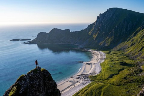 Climber on a rock, view of picturesque coastal landscape, steep coast with peak Måtind or Måtinden,