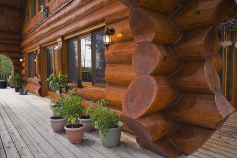 Brown reddish stained Scandinavian log cabin home facade with large chinked logs and grey wood