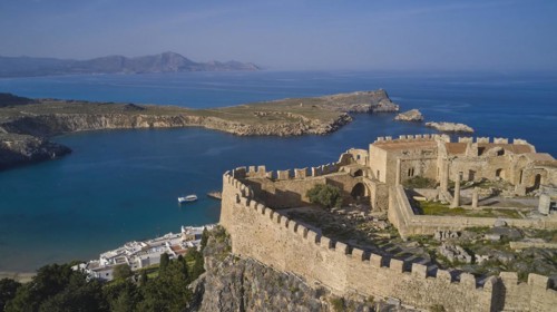Drone shot, Acropolis of Lindos, Late afternoon light, Ancient fortress on a headland above a blue