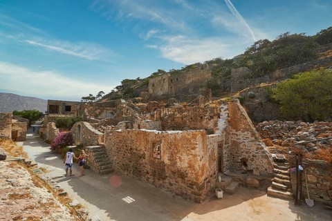 Tourists walking through an ancient village with ruins and pathways on a sunny day, Venetian Sea