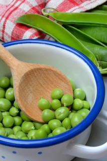 Fresh green peas in pot with wooden spoon, Pisum sativum
